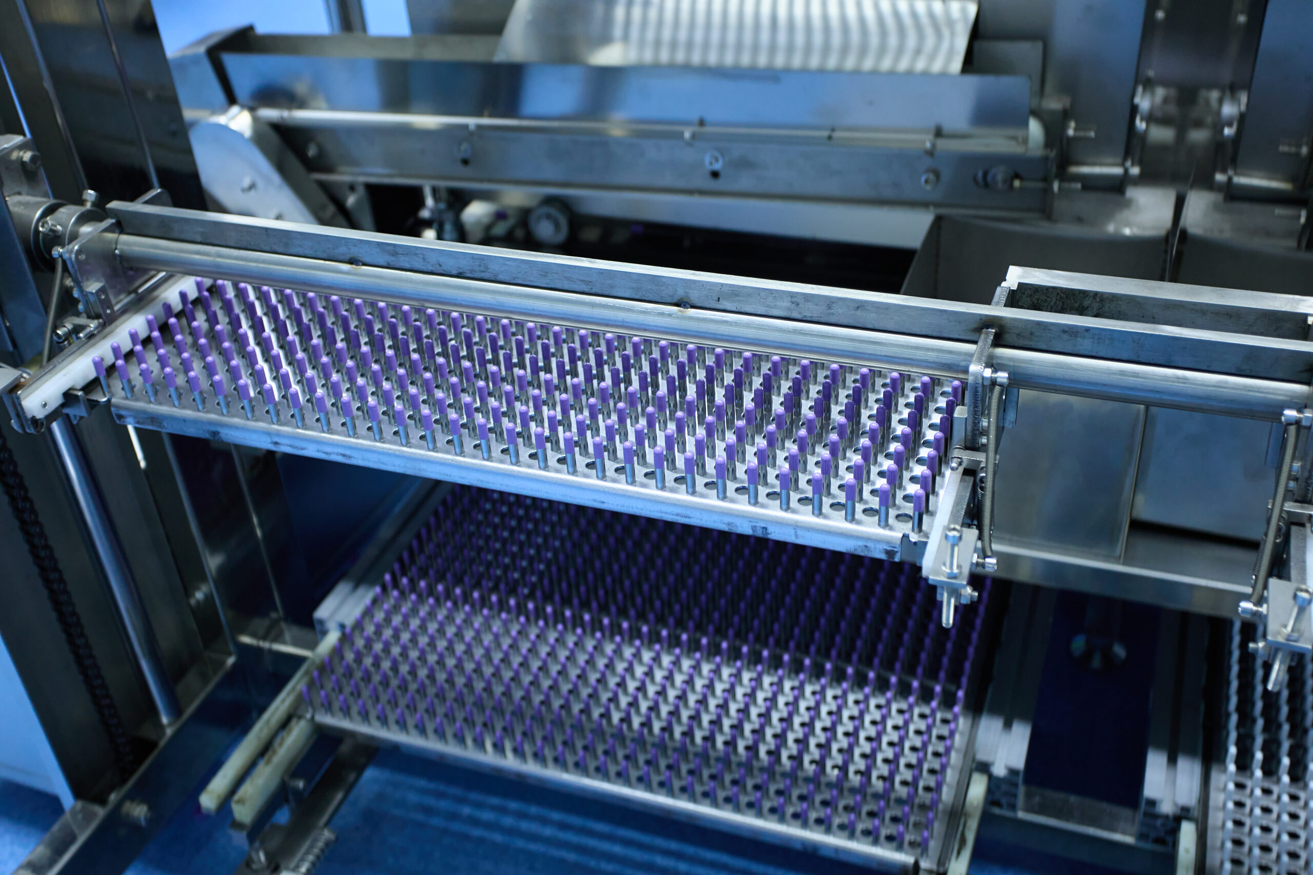 A close-up of a pristine, stainless steel capsule production machine being cleaned